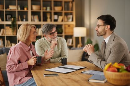 Senior couple discussing personal finances with financial advisor at home 