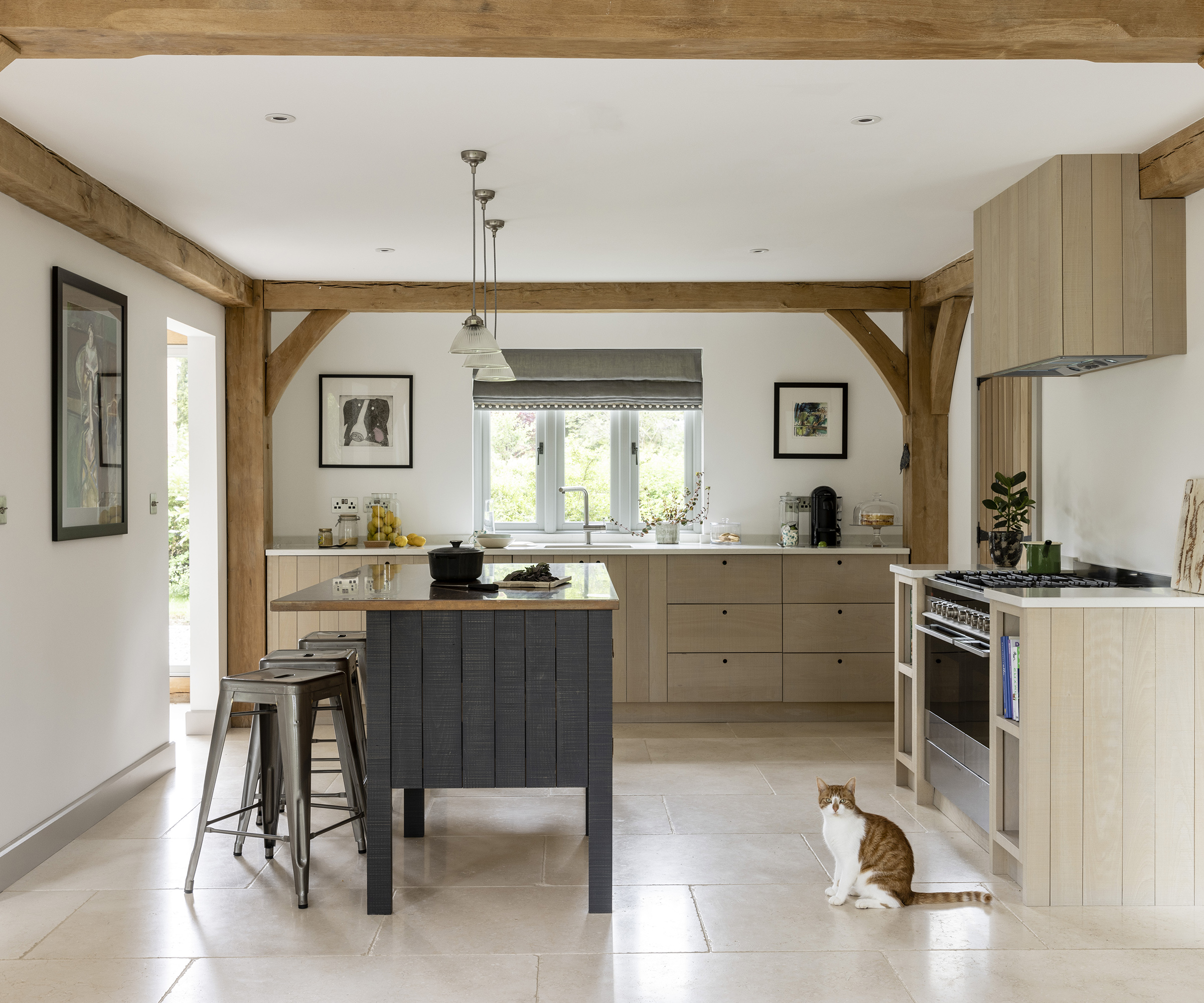 A modern but rustic kitchen with wooden cabinets and light tiled floor. THere is a free standing kitchen island and a cat