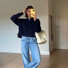  @smythsisters taking a mirror selfie in jeans and a navy sweater, with a cream leather tote and yellow iPhone case.