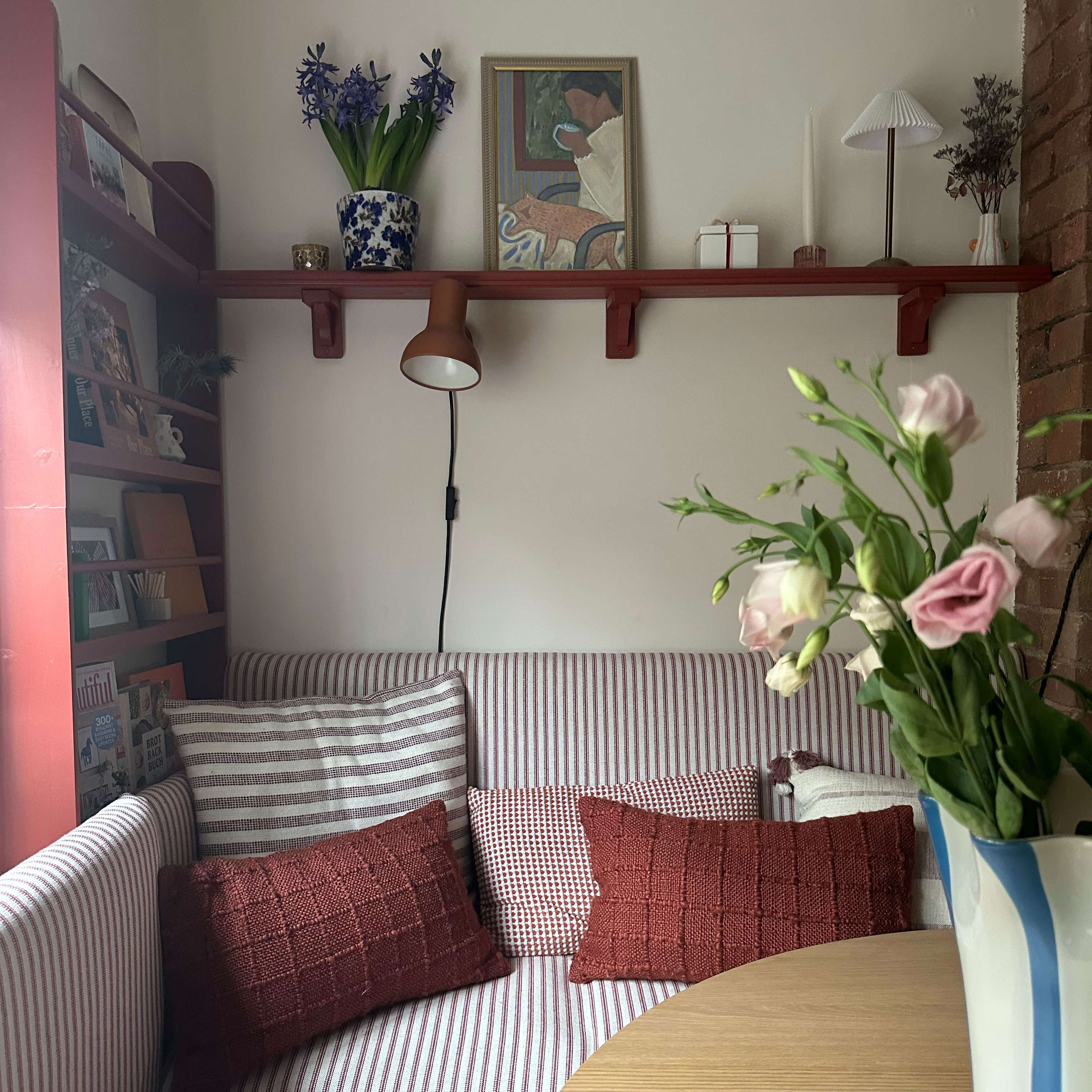 Corner kitchen banquette in striped fabric with mix and match cushions beneath red shelf