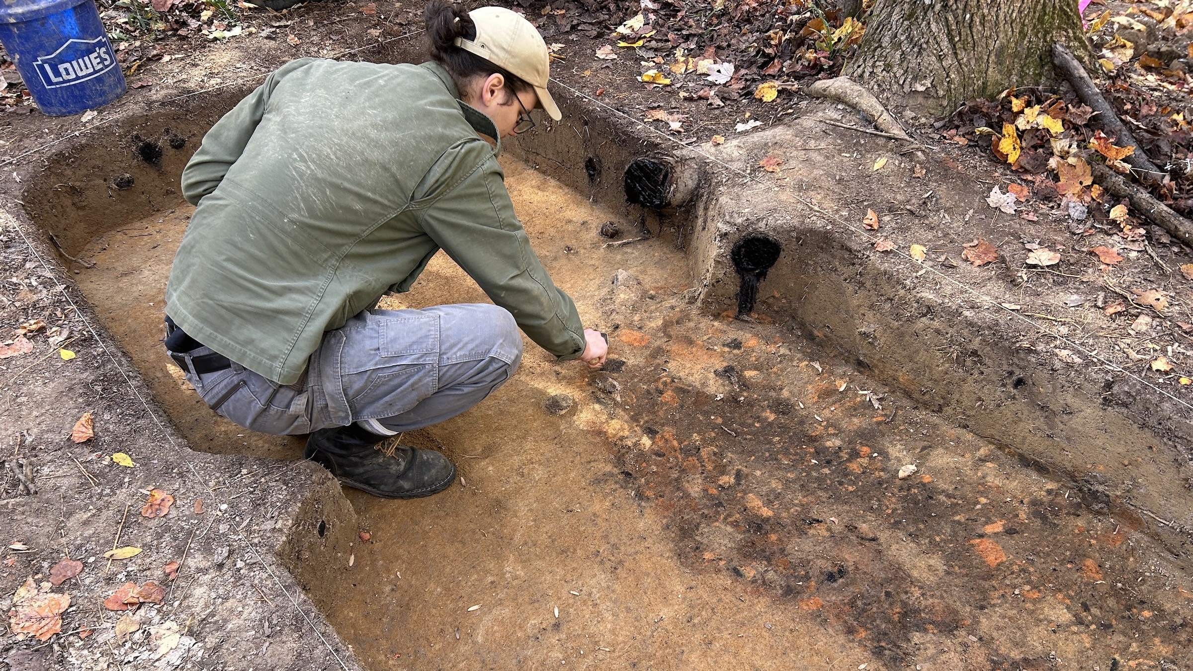 An excavator is in an excavated rectangular area in the woods