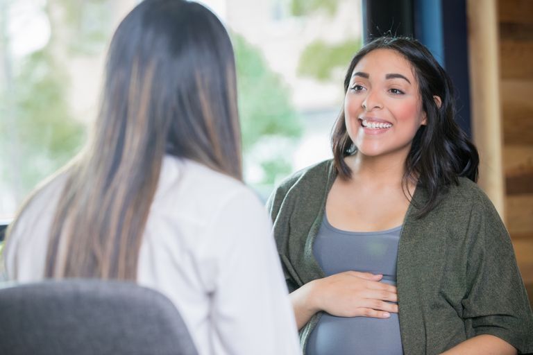 Hispanic woman discussing her pregnancy with midwife