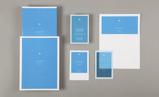 Six light blue posters with the words Lacoste written in the centre of each. Each poster varies in size.