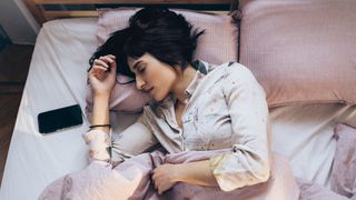 A woman lies in bed listening to soothing white noise from a smartphone app