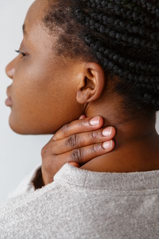 Woman touching back of her neck.