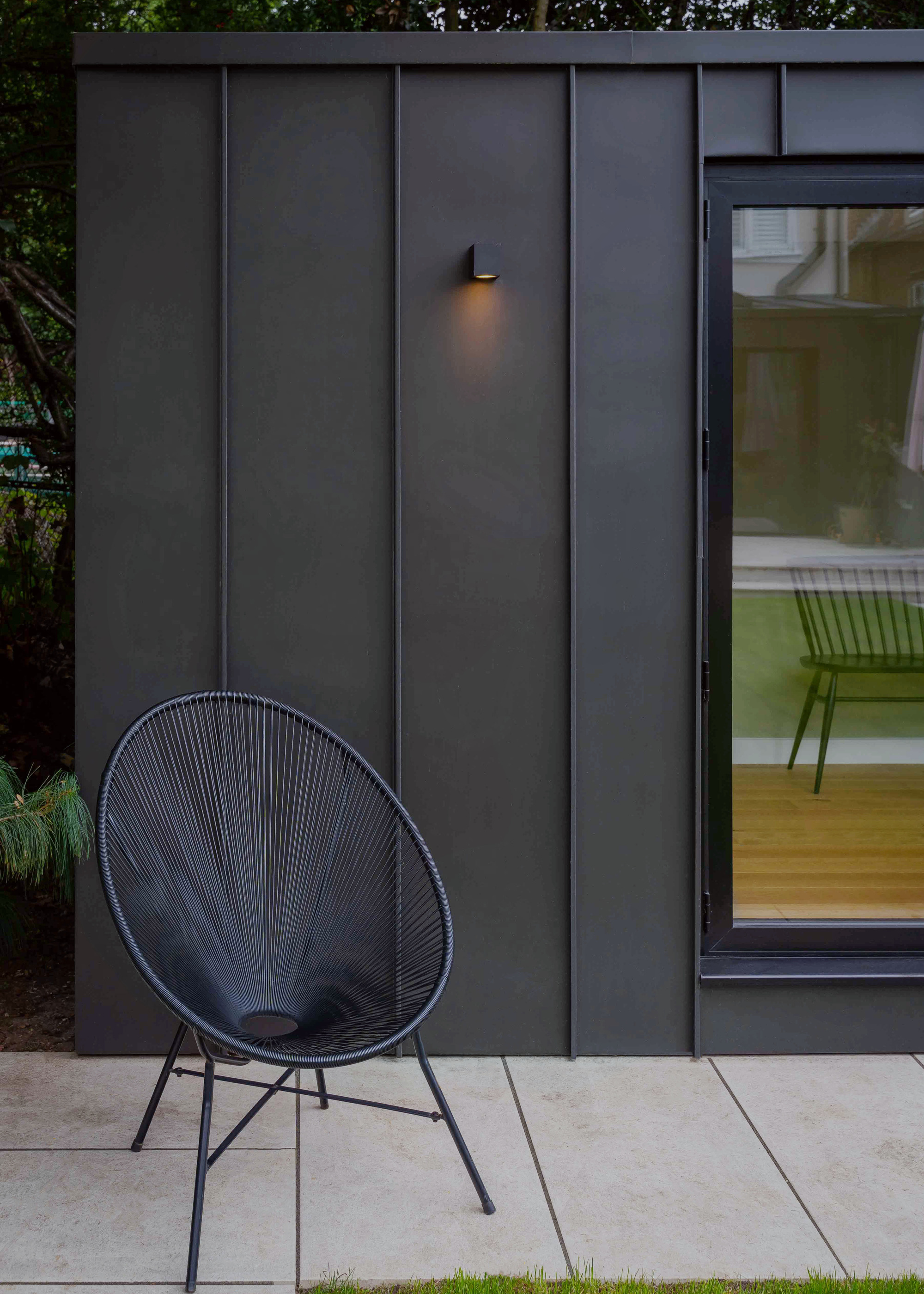 black clad garden room with black chair outside