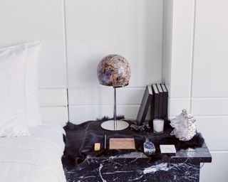crystal on side table next to a bed with white sheets