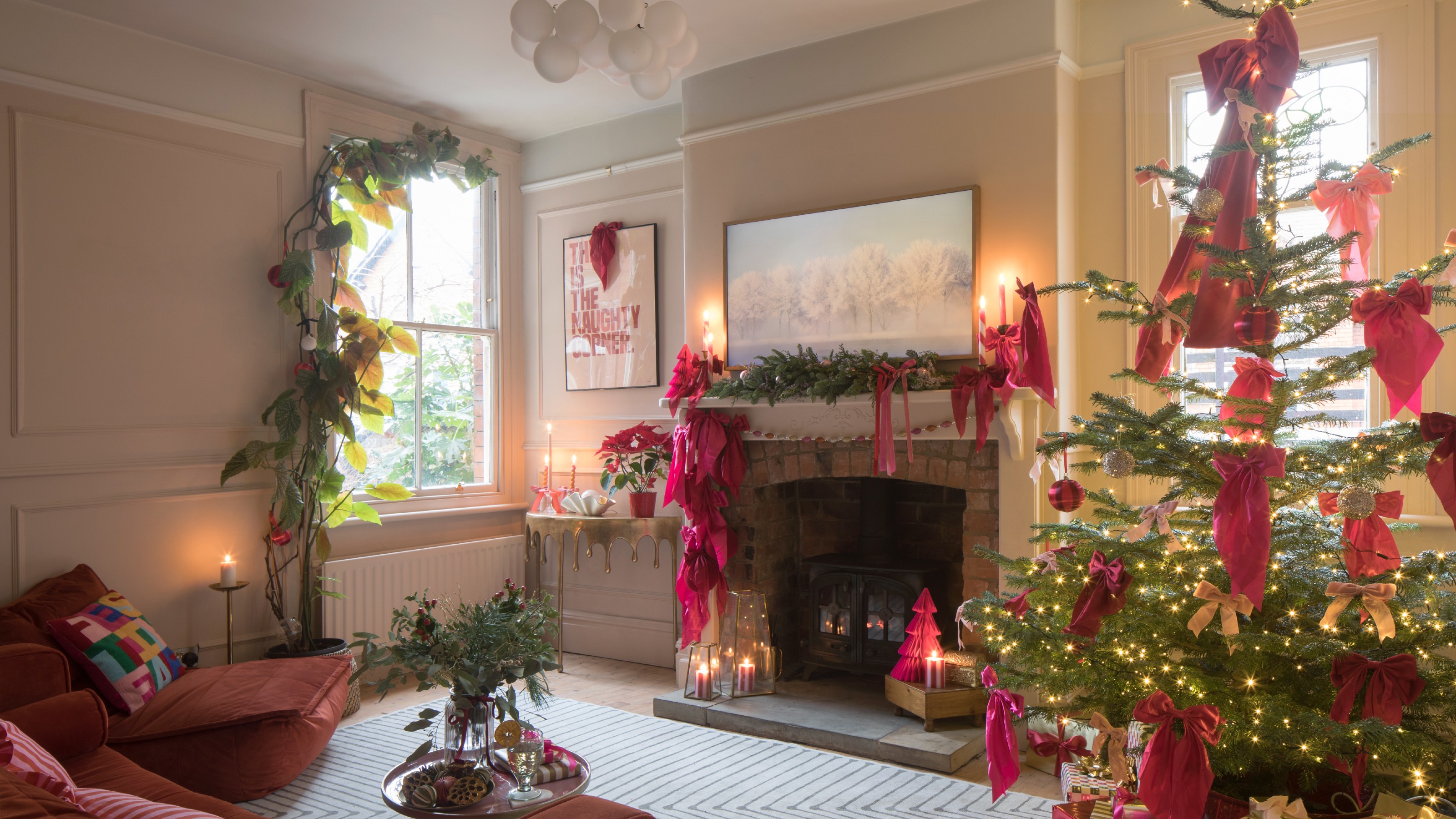 A living room decorated for Christmas with pink bows all over the tree and the fireplace