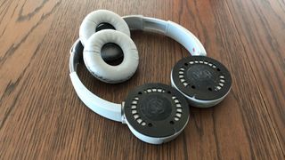 A pair of headphones with the ear pads removed on a wooden table