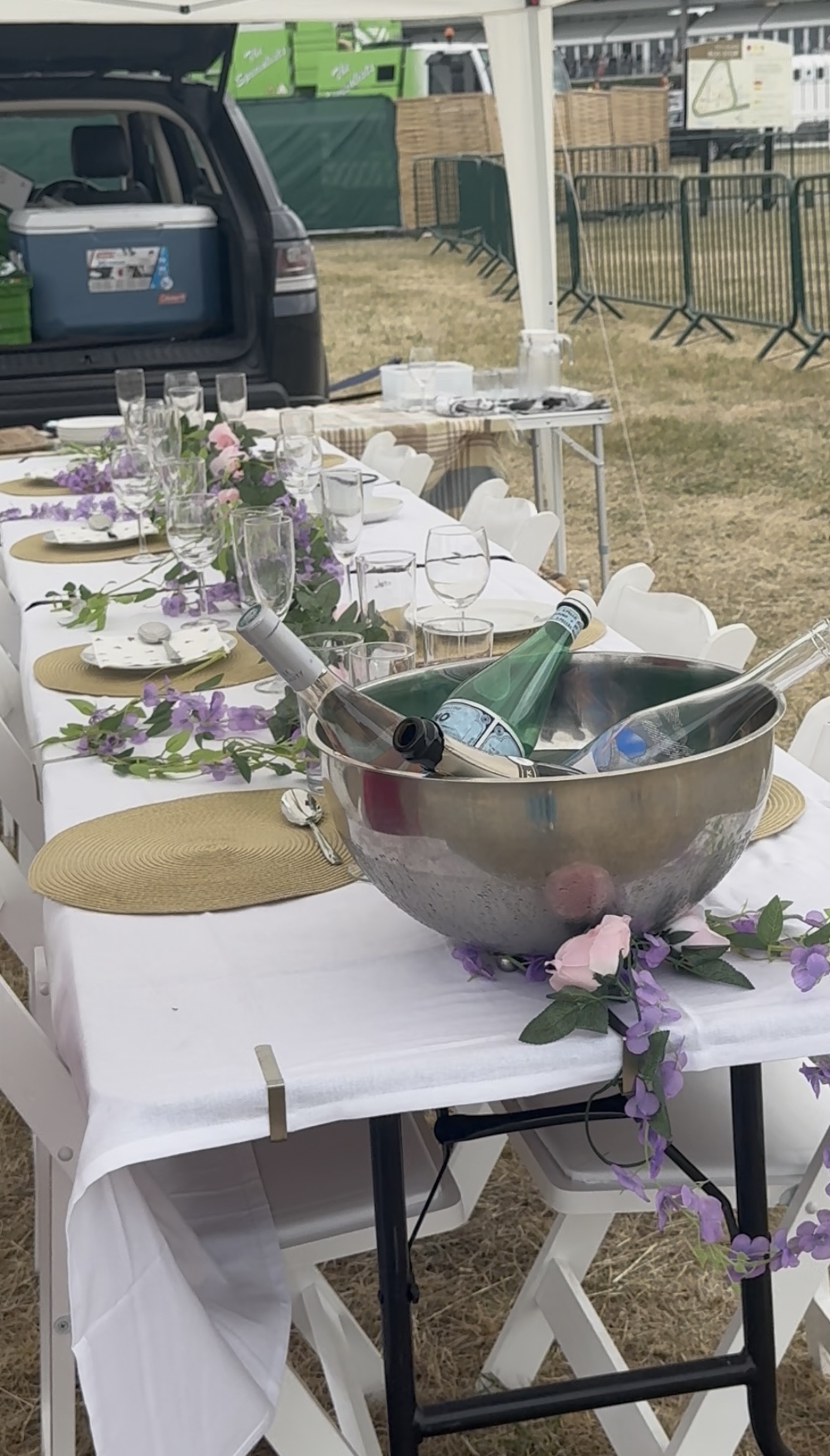 A table in front of a car with champagne and purple flowers on it