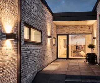 Exterior cube outdoor wall lights on a brick wall leading to a modern front door