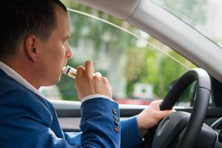 man vaping in car with window open
