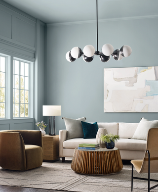 A living room painted a steely blue shade with a large cream sofa and natural accents