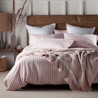 A bedroom with a bed covered in pink and white striped brushed cotton bedding