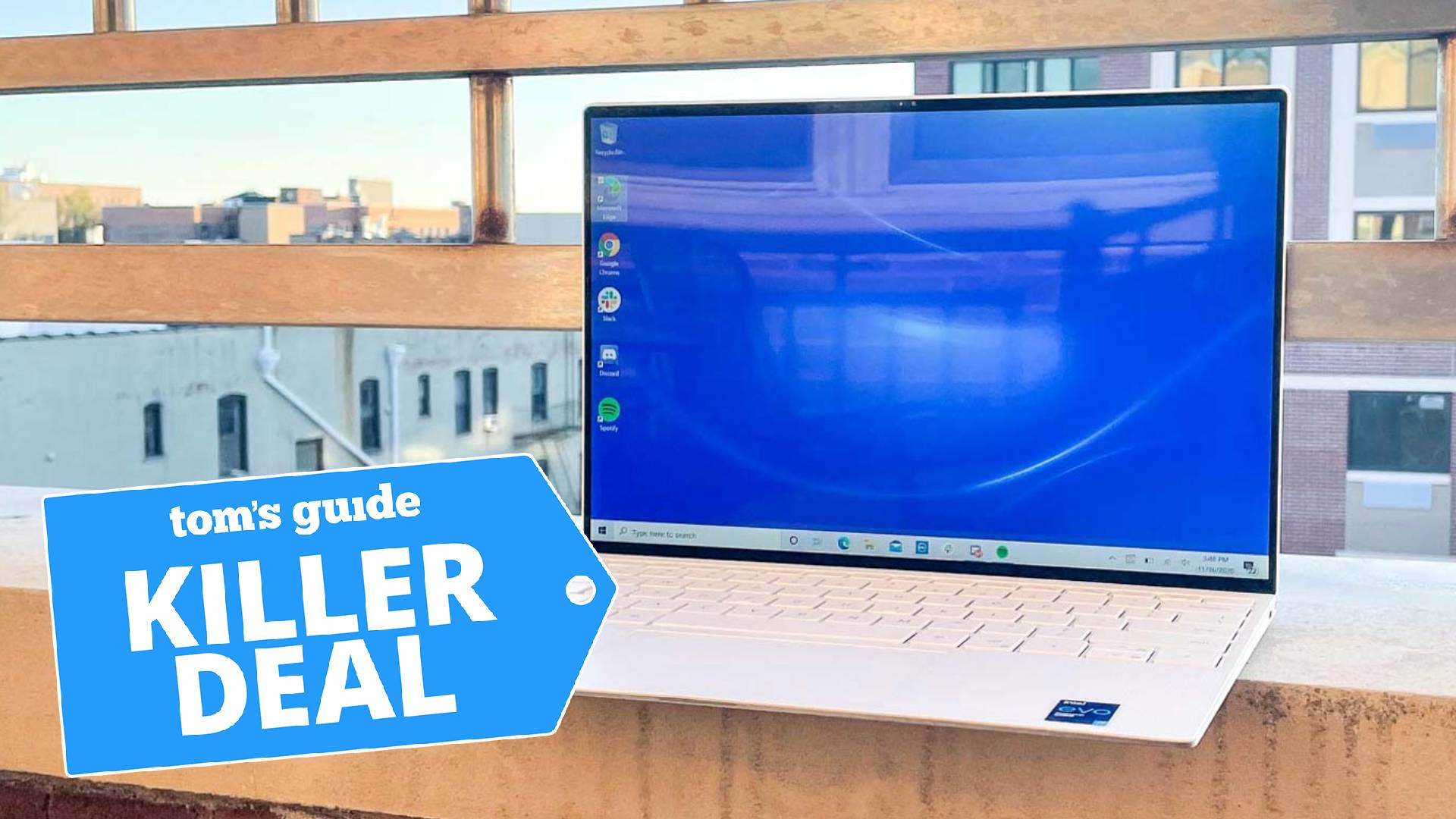 A photo of the Dell XPS 13 laptop on a windowsill outlooking a cityscape. The "Tom's Guide killer deal" tag is overlaid.