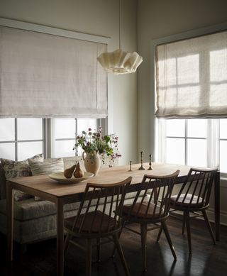 dining table in dark wood, placed in corner of room with windows on both walls, dark floors