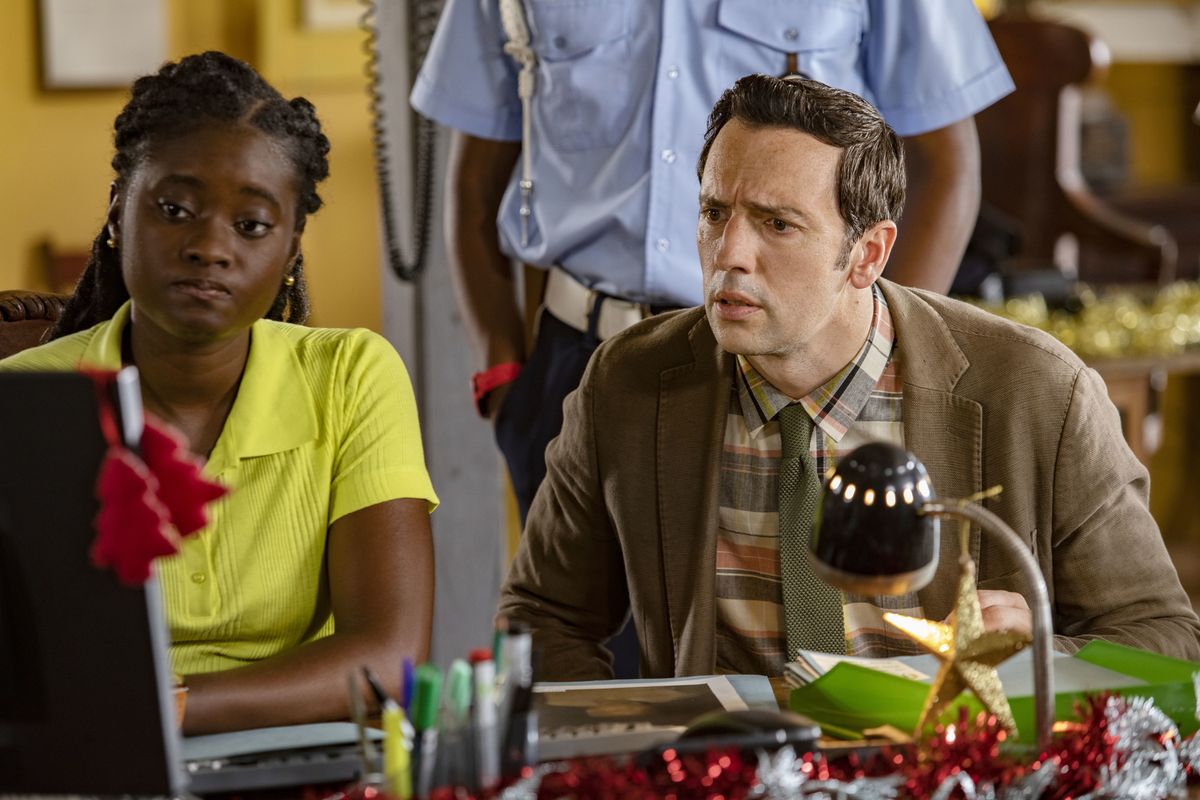 Naomi (Shantol Jackson) and Neville (Ralf Little) sit at a desk in the police station looking at the computer