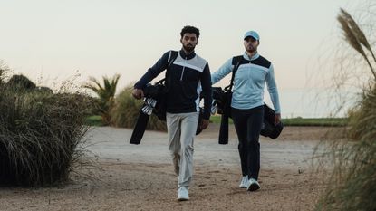 Two golfers walking while carrying their bags