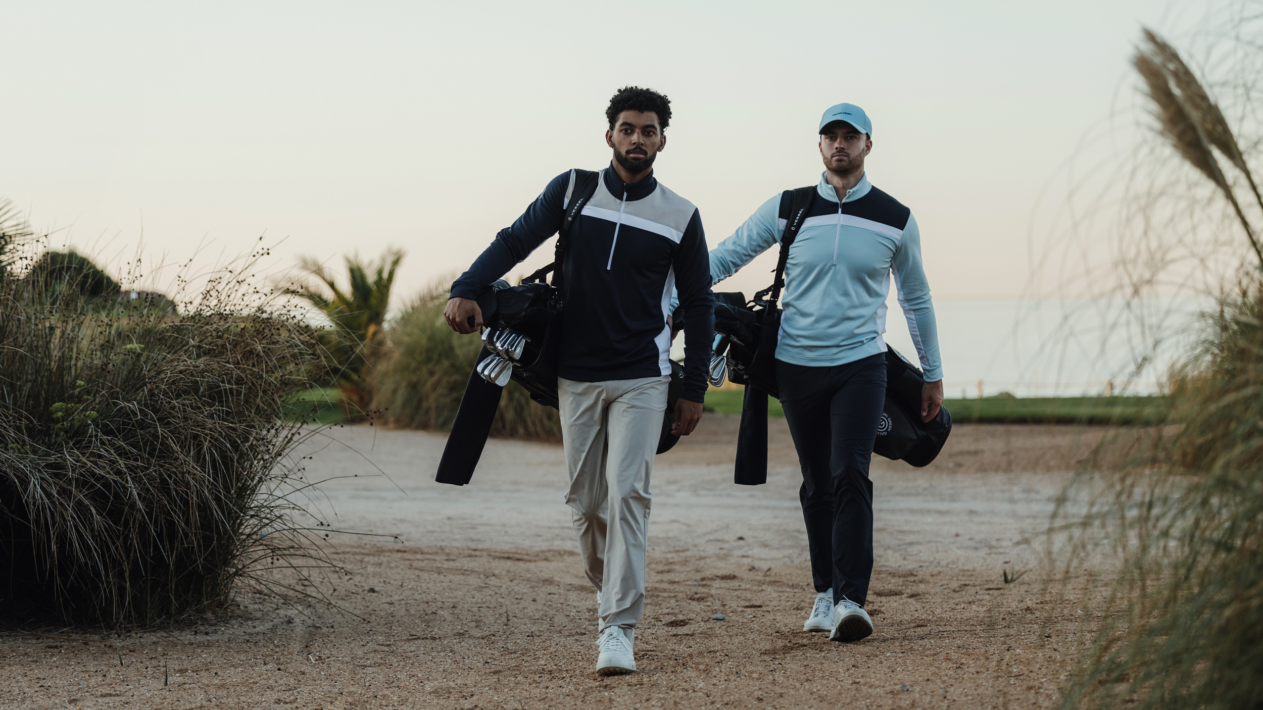 Two golfers walking while carrying their bags