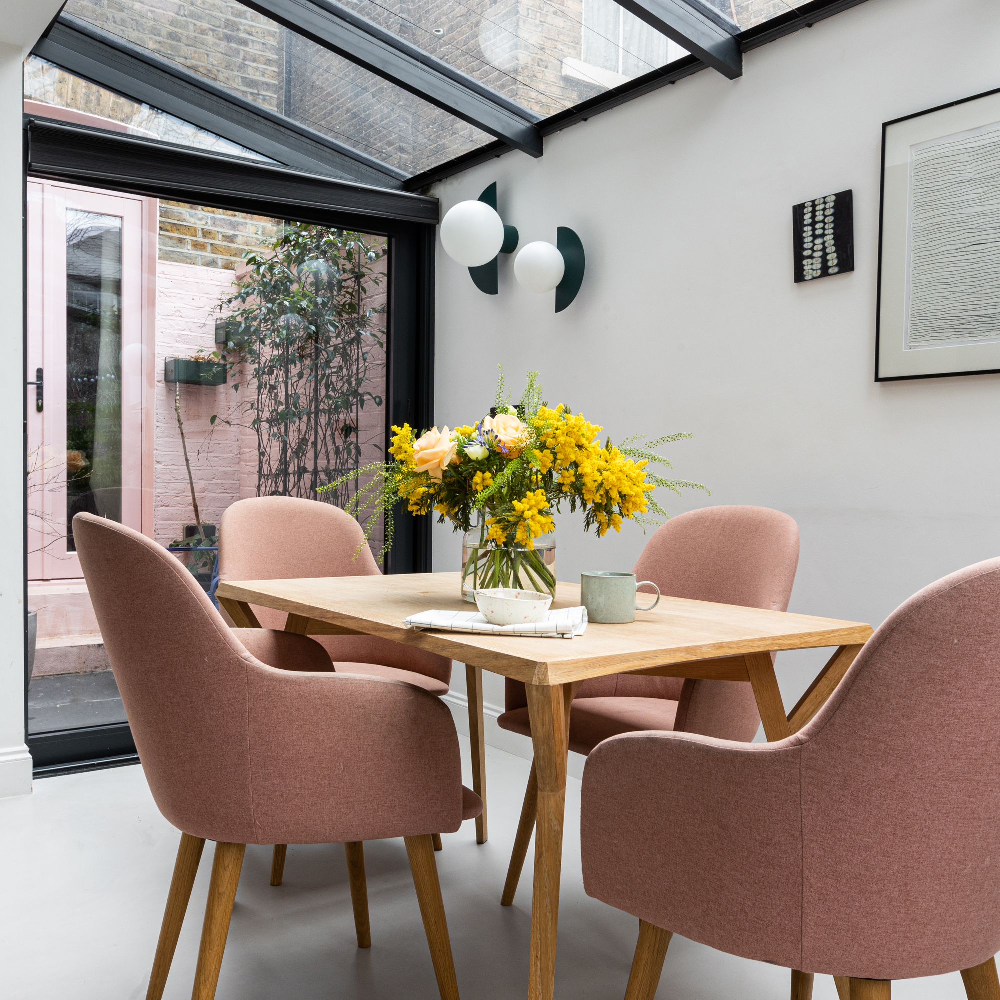 a side return extension with a wooden dining table and pink upholstered dining chairs