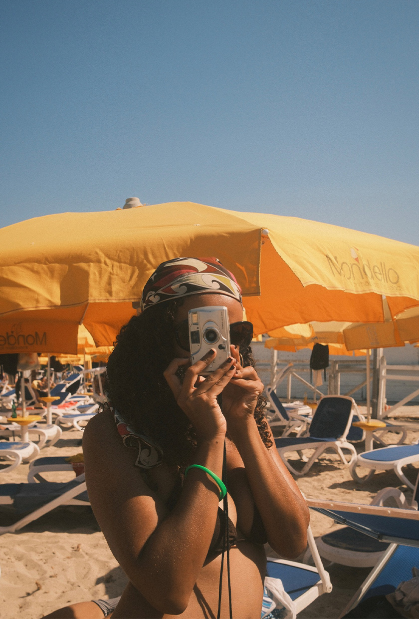 How to pack for Italy is shown in a picture of a fashion editor wearing a silk printed headscarf styled with a brown bikini