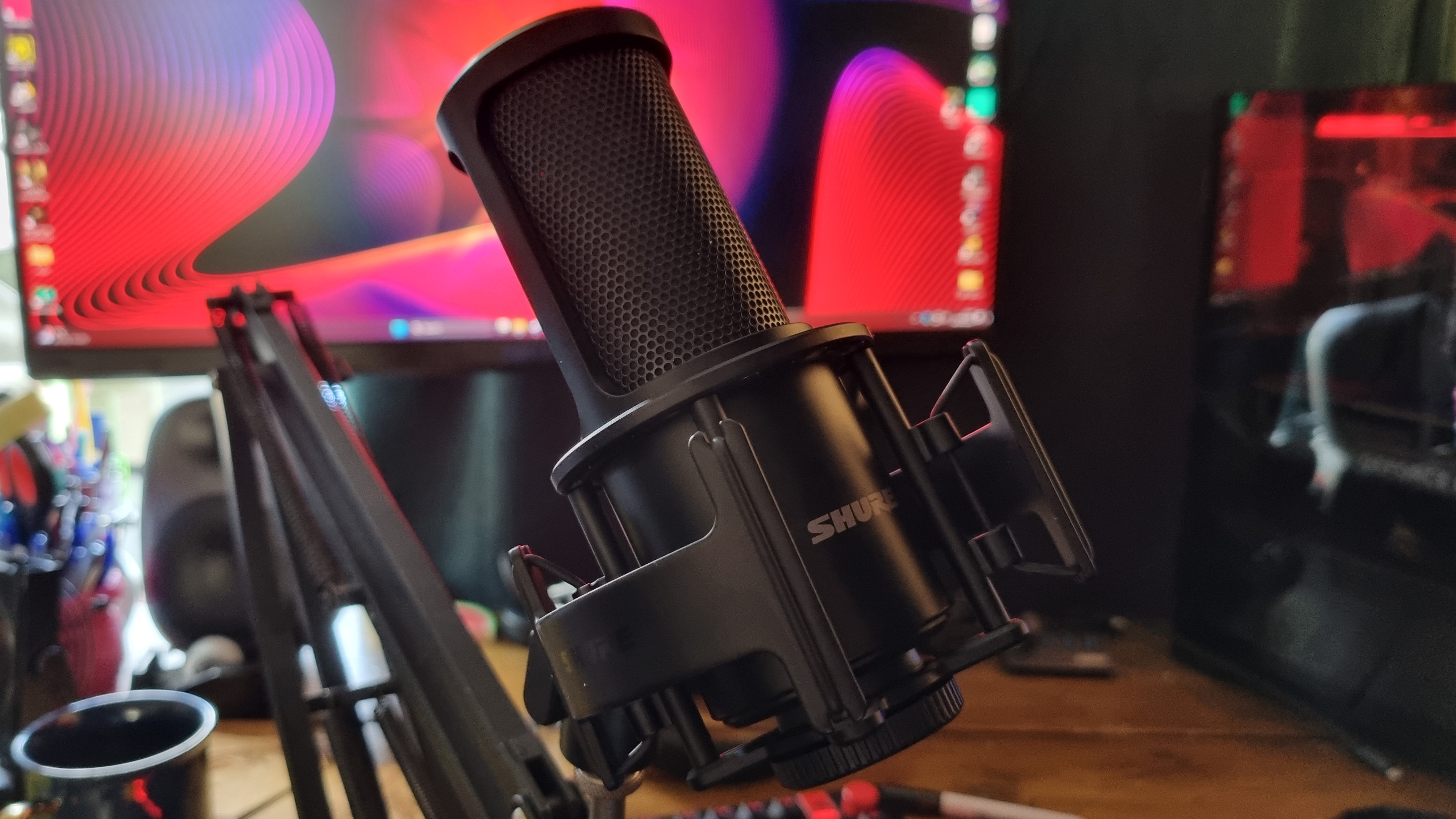 The Shure SM4 home recording microphone attached to a boom arm, in front of a monitor