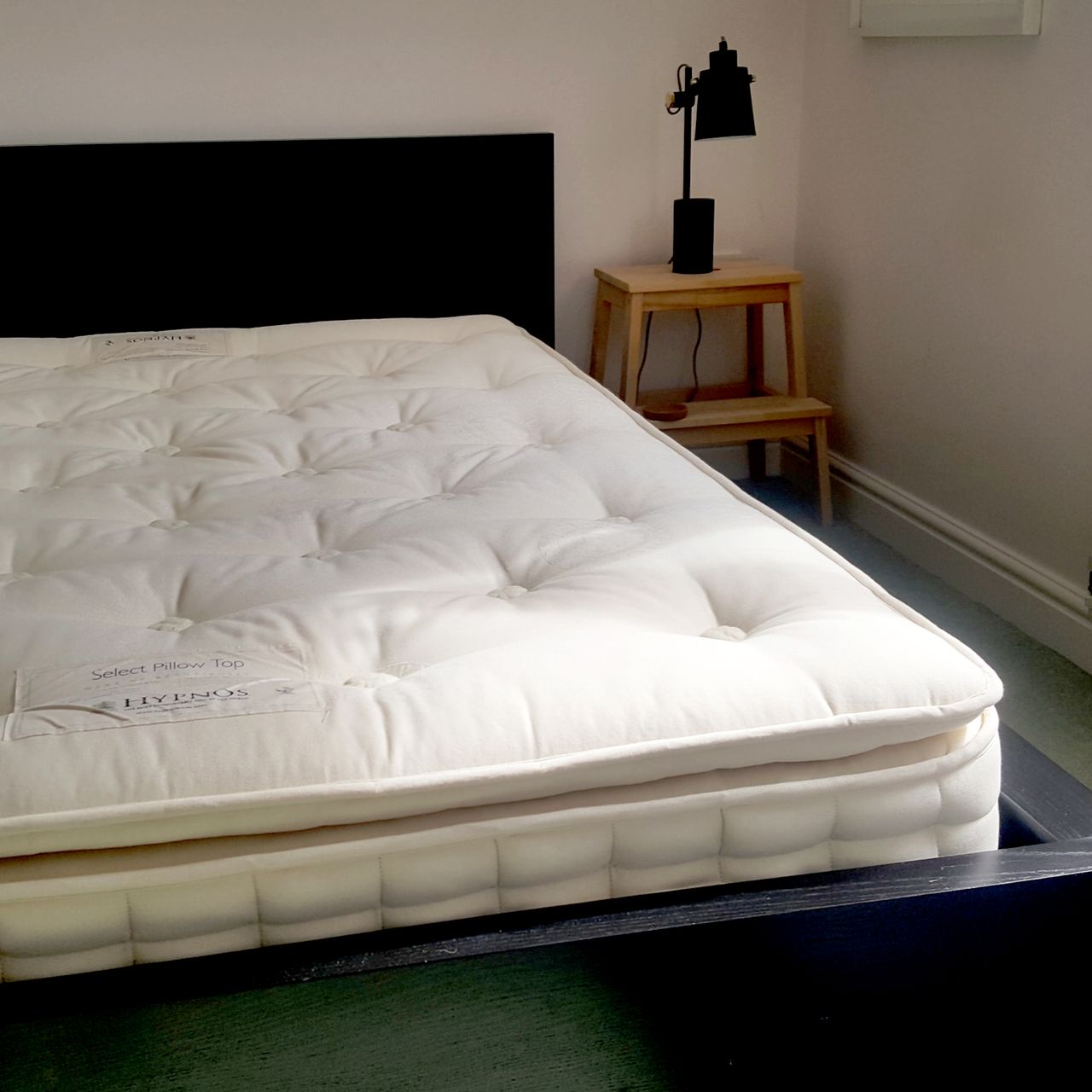 The Hypnos Pillow Top Classic mattress being tested in a bedroom with pale pink walls and a black bed