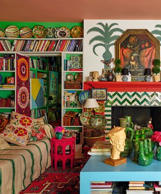 maximalist living space with full bookshelves and mural on wall an zig zag tiled fireplace