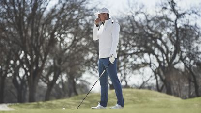 Best golf waterproofs for golf: Pictured here, a young man in on the golf course eyeing up the distance