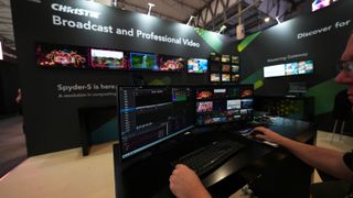 A person sits in front of two computer monitors at a trade show booth.