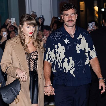 Taylor Swift in a camel coat and black and nude corset dress while holding hands with boyfriend Travis Kelce while out in New York City. 