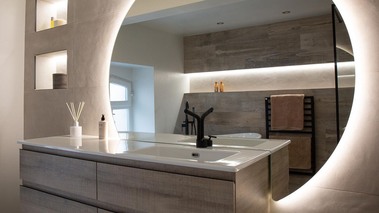 en suite bathroom with round mirror and wall hung vanity