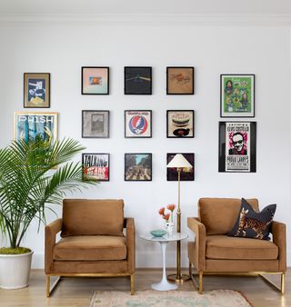living room with white walls and brown armchairs with record covers on the wall