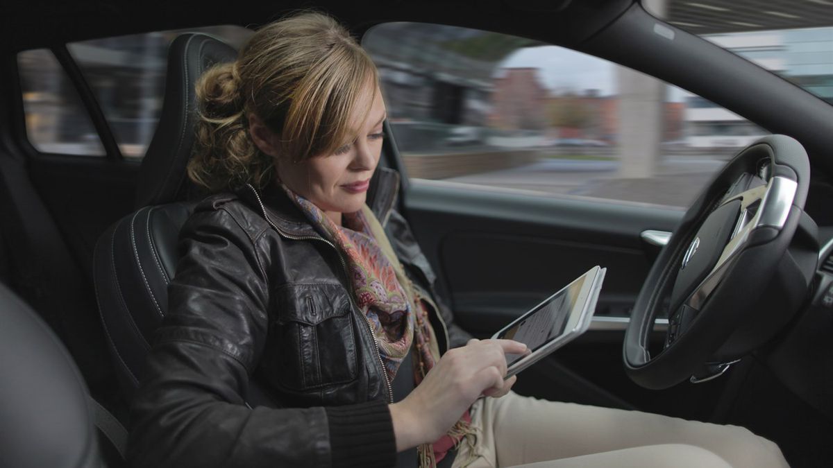 Woman travelling in driverless car using iPad