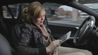 Woman travelling in driverless car using iPad