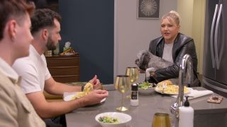 Nick Dorka (near left) and Hannah Jiles (right, holding a puppy), have dinner with Hannah's brother Cade (far left) at their kitchen island, in 'Love is Blind' season 7.