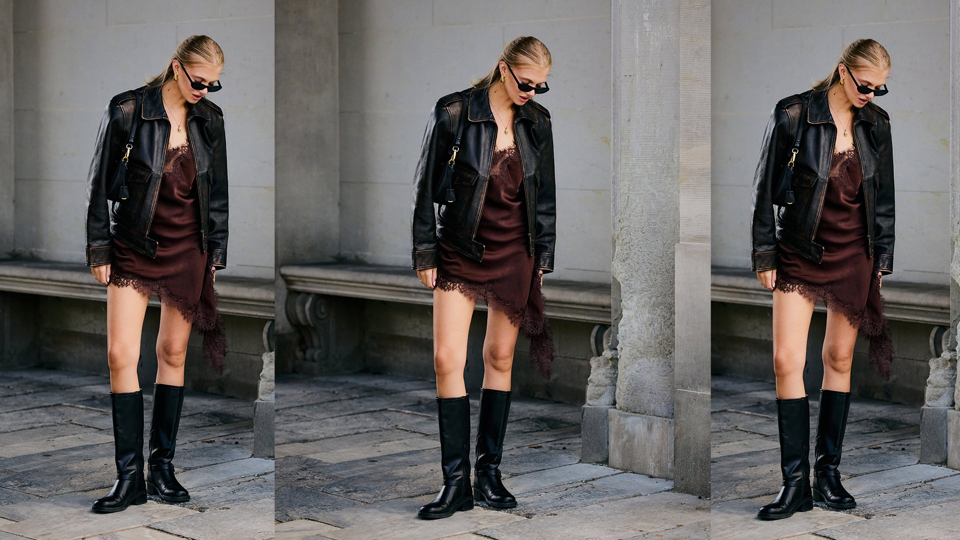 Woman wears asymmetrical brown satin dress with a lace trim. She also has on tall flat black boots along with a black motorcycle style leather jacket. 