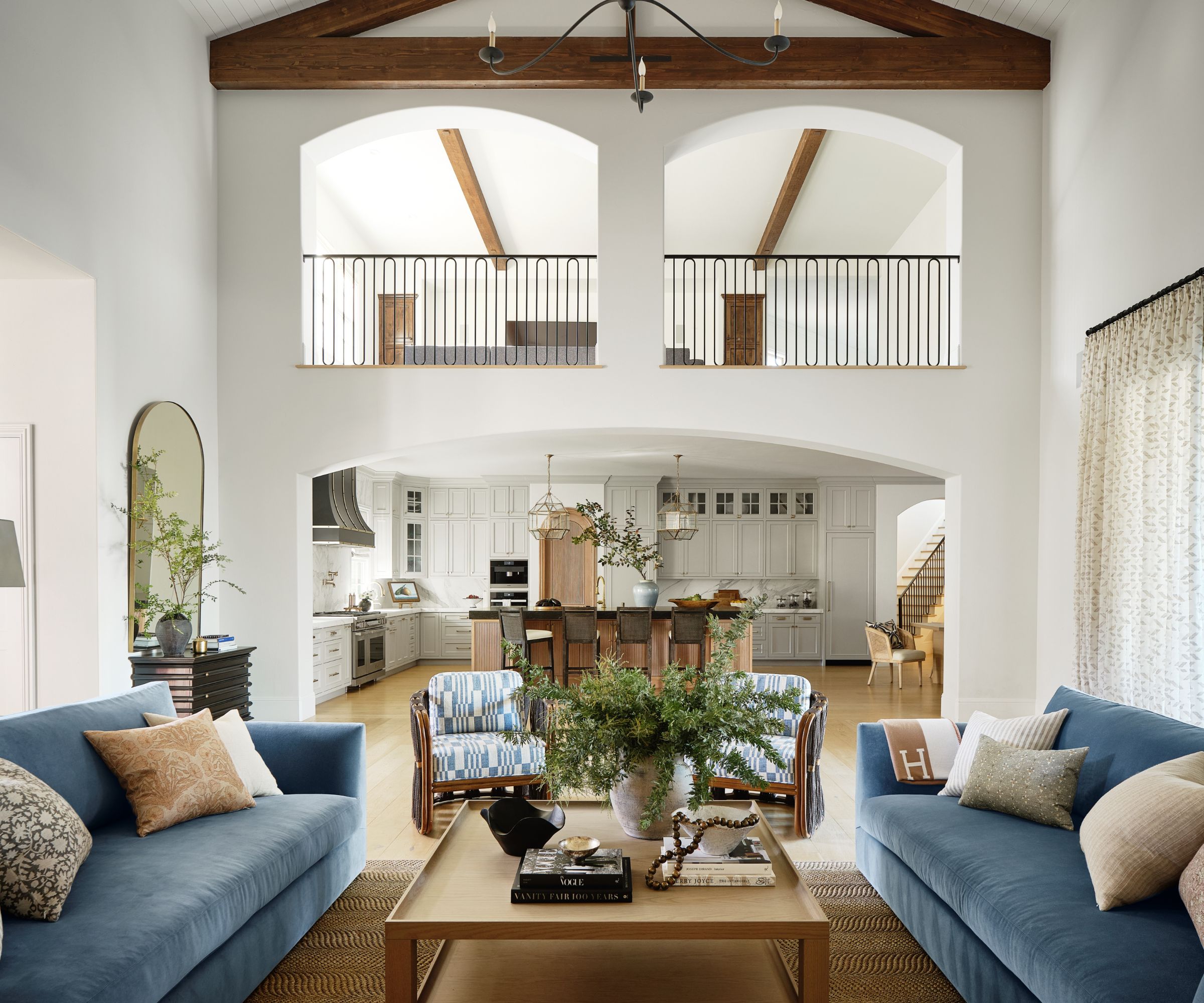 family living room blue sofas view to kitchen with white walls mezzanine and beams