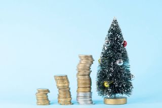 Growing piles of coins close to a Christmas tree.