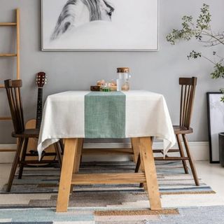 A beige and green tablecloth on a wooden dining table