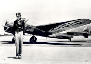 Amelia Earhart, who has a tall, thin body, stands in front of the Lockheed Electra in which she disappeared in July 1937. 