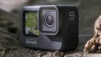 The GoPro Hero 9 Black sitting on a tree branch showing its front-facing screen