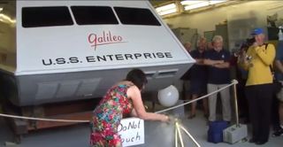 Leslie Schneider breaks a bottle of champagne to rechristen the restored Galileo shuttlecraft, an original set prop from the 1960s