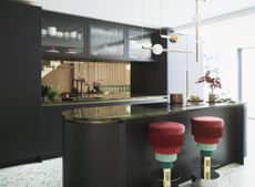 black kitchen with terrazzo flooring, gloss counterop, red and green fringed bar stools, retro pendant lights, curvy kitchen island 