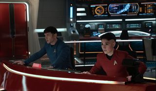 two star trek characters sit at a console aboard their ship
