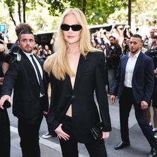 a white woman in a black jacket with sunglasses surrounded by photographers