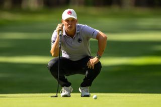 Caleb Surratt crouches down behind a putt at the 2024 International Series England