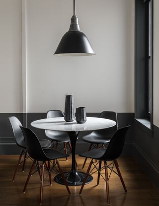 A white and black breakfast room with a black line of paint along the lower half of the wall