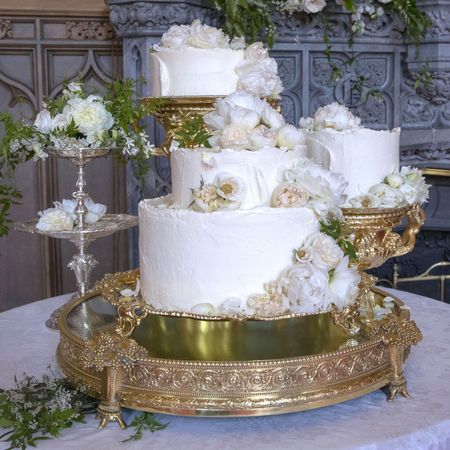 Meghan Markle and Prince Harry's white tiered wedding cake covered in flowers on a gold tiered stand 