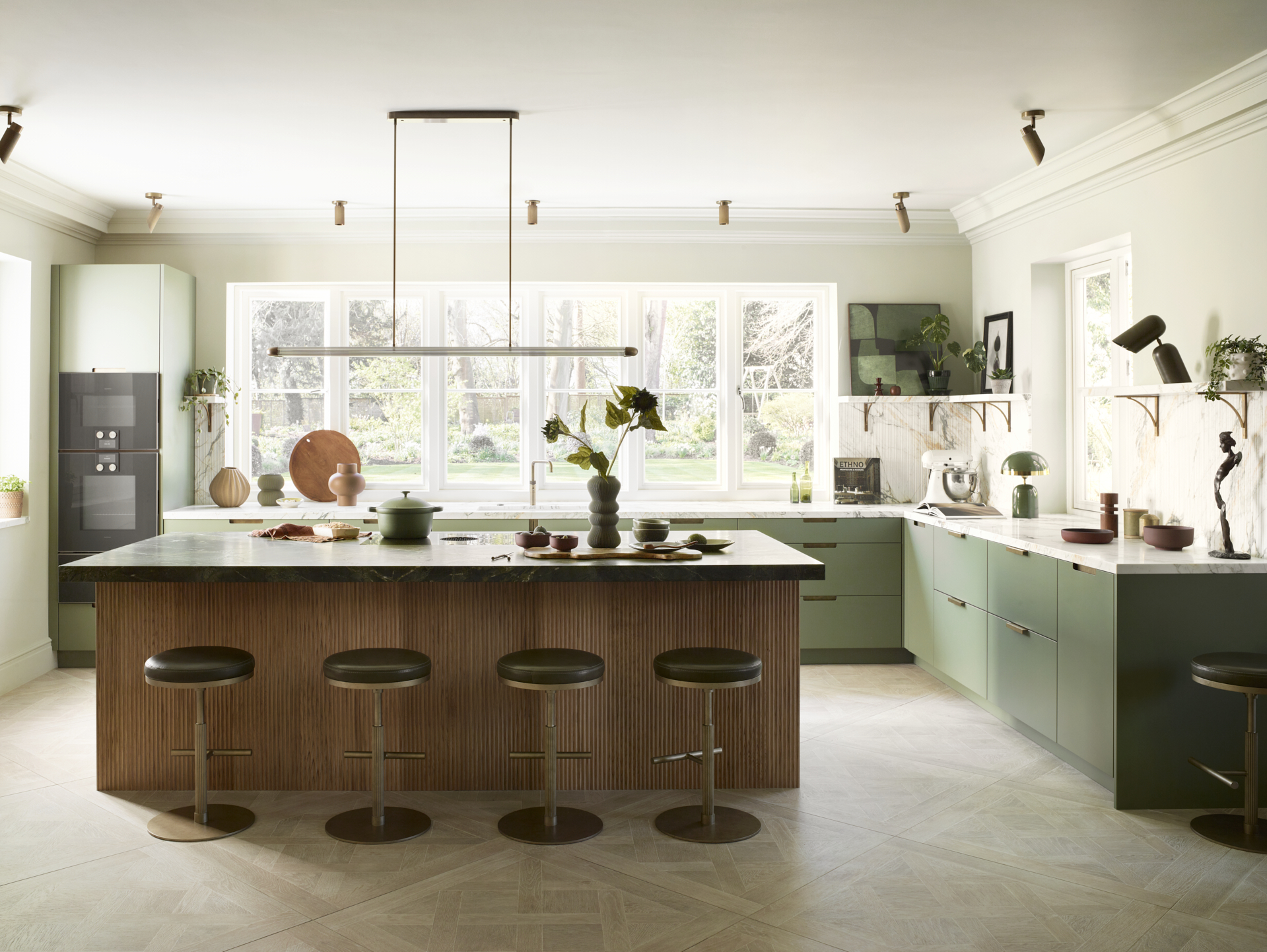 large kitchen with sage green cabinetry and a fluted wooden island